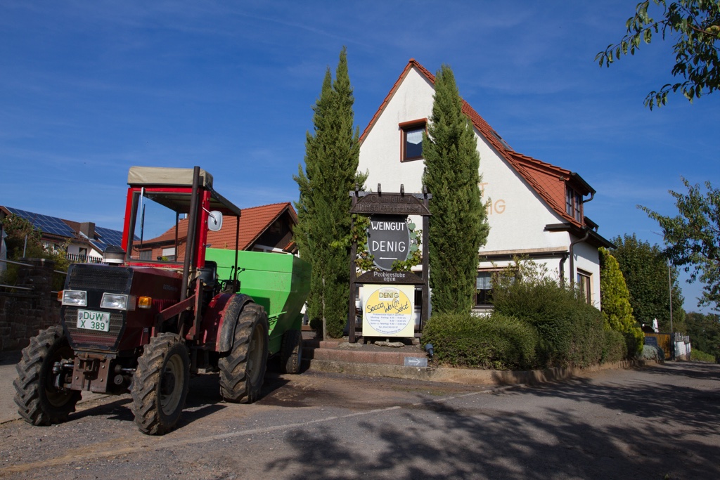 Foto vom Weingut, mit Schild und Traktor im Vordergrund